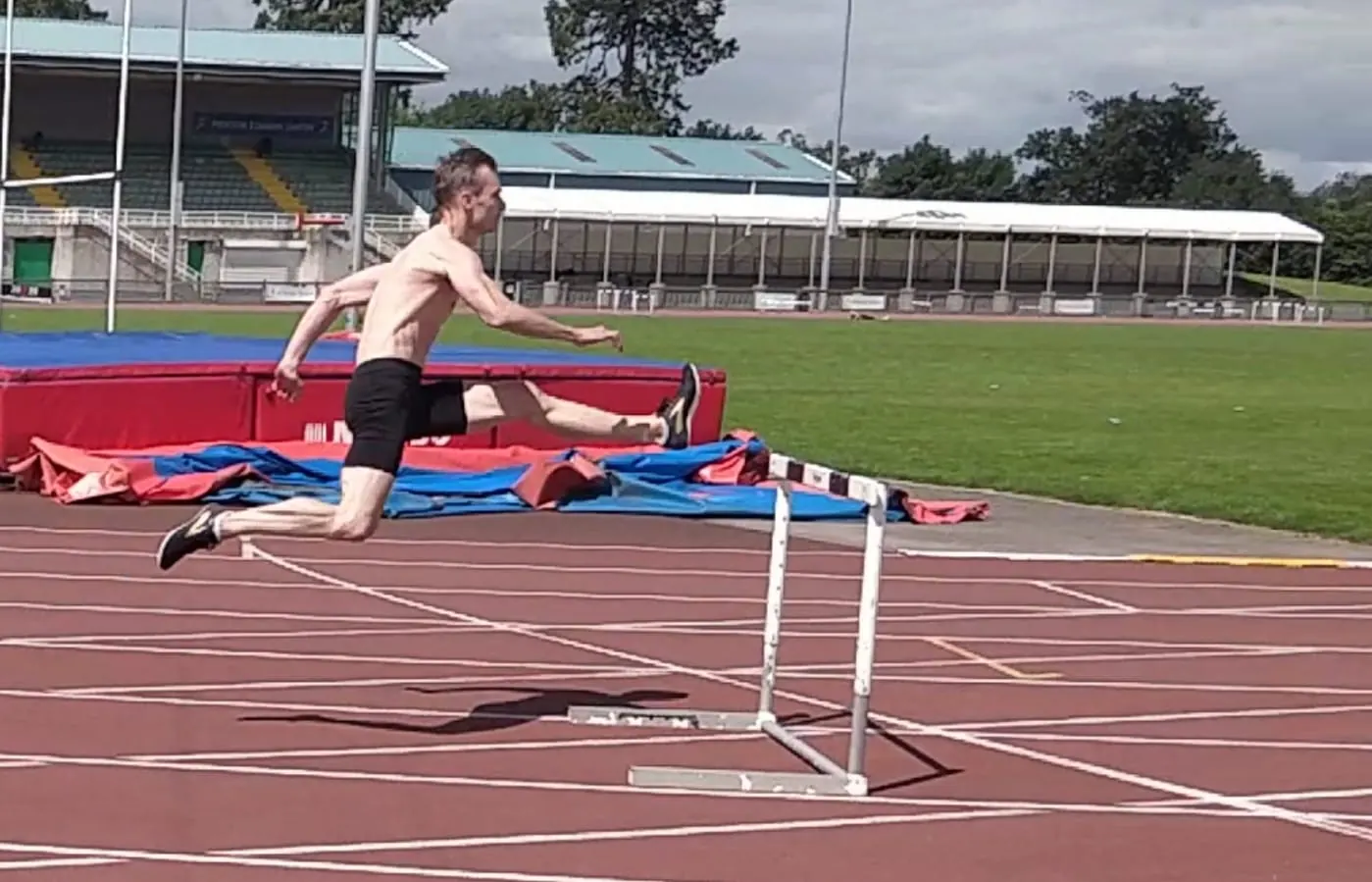 John Fagan clearing a hurdle on an athletics track